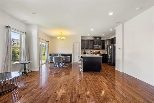 a kitchen with stainless steel appliances granite countertop a refrigerator a stove top oven a sink dishwasher and a dining table with wooden floor