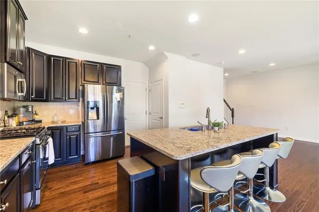 a kitchen with stainless steel appliances granite countertop a table chairs and stove