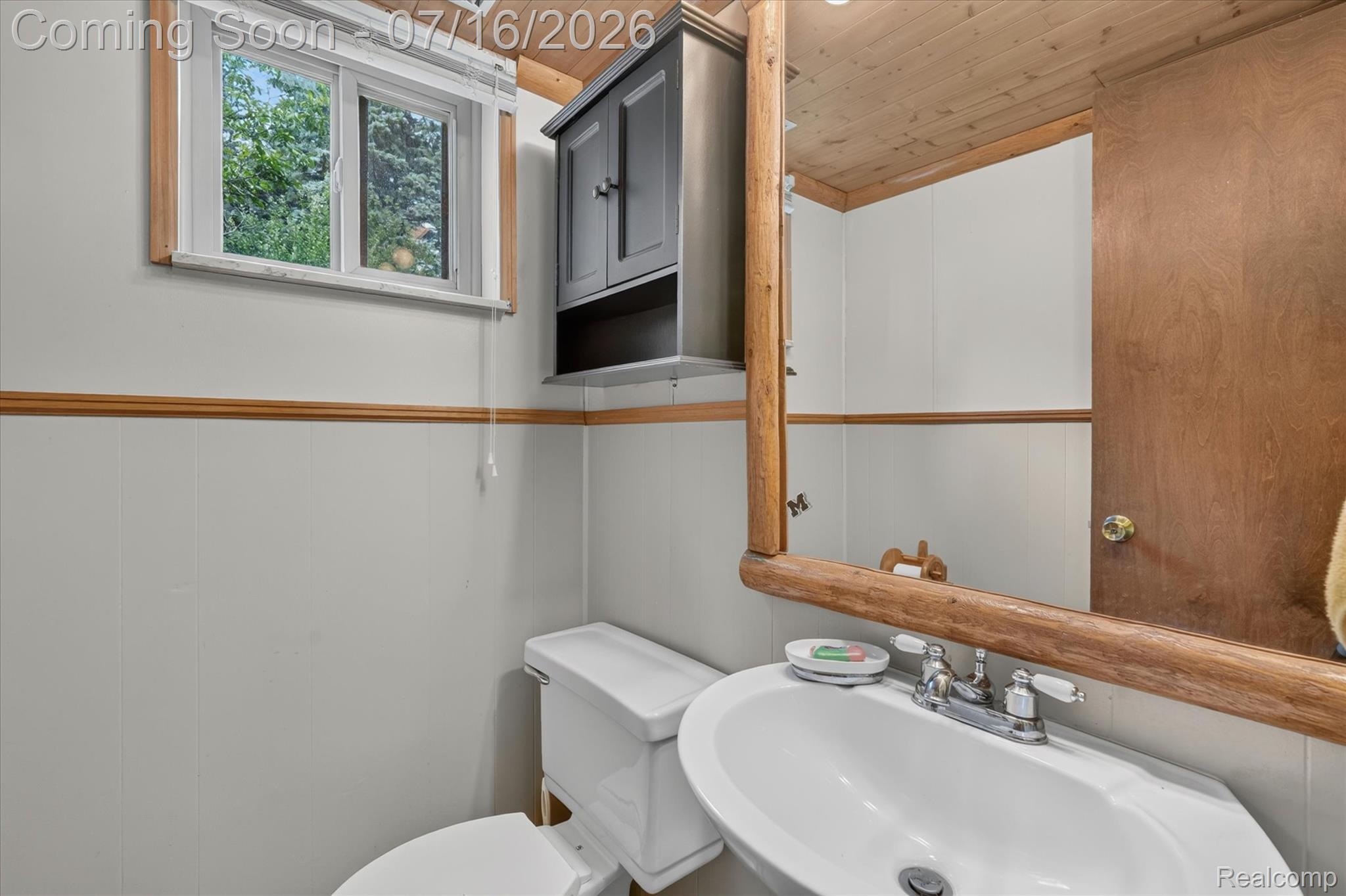 11210 Linden Road Linden, MI 48451 - Photo 26 of 61 White vanity sink with chrome faucet, complemented by a wood-framed mirror and a dark gray wall cabinet