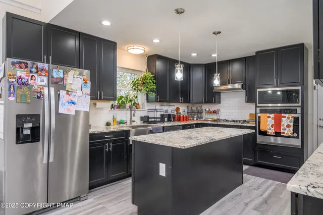 a kitchen with stainless steel appliances kitchen island granite countertop a refrigerator sink and stove