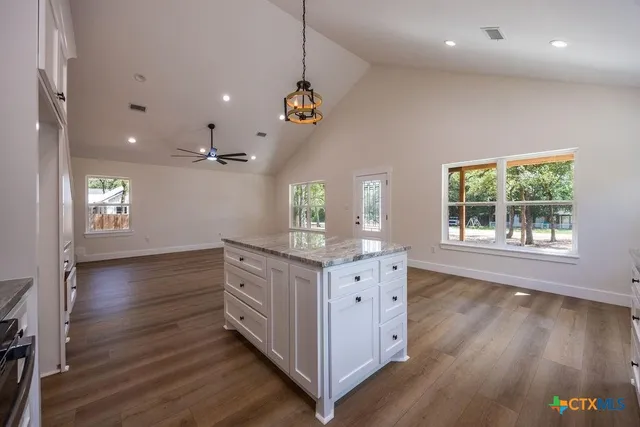 a kitchen with granite countertop a stove a sink a window and wooden floors