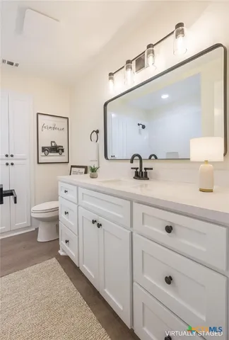 a spacious bathroom with double sink a large mirror and a toilet