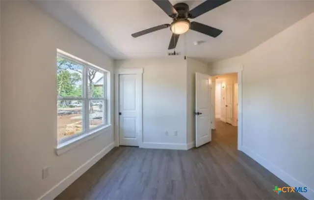 an empty room with wooden floor fan and windows