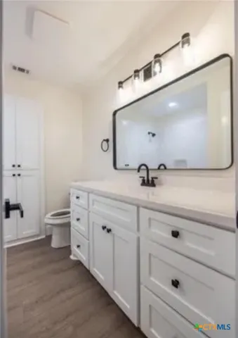 a bathroom with a double vanity sink a toilet and a mirror