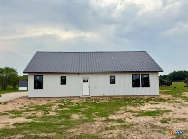 a backyard of a house with large trees and wooden fence