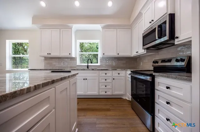 a kitchen with stainless steel appliances granite countertop a stove a sink and a microwave