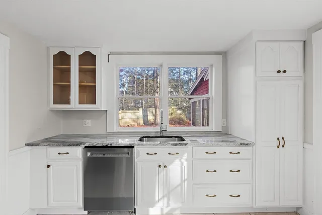 a kitchen with granite countertop white cabinets and window