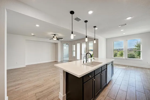 a kitchen with a sink chandelier and wooden floor
