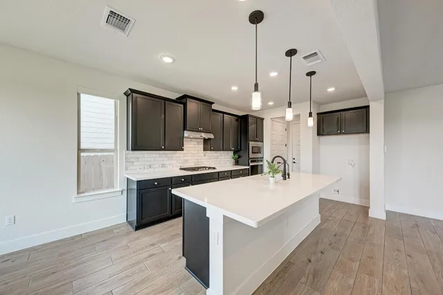 a large kitchen with stainless steel appliances kitchen island a large counter top and a fireplace