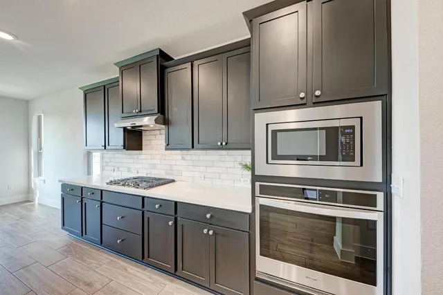 a kitchen with kitchen island granite countertop a sink cabinets and stainless steel appliances