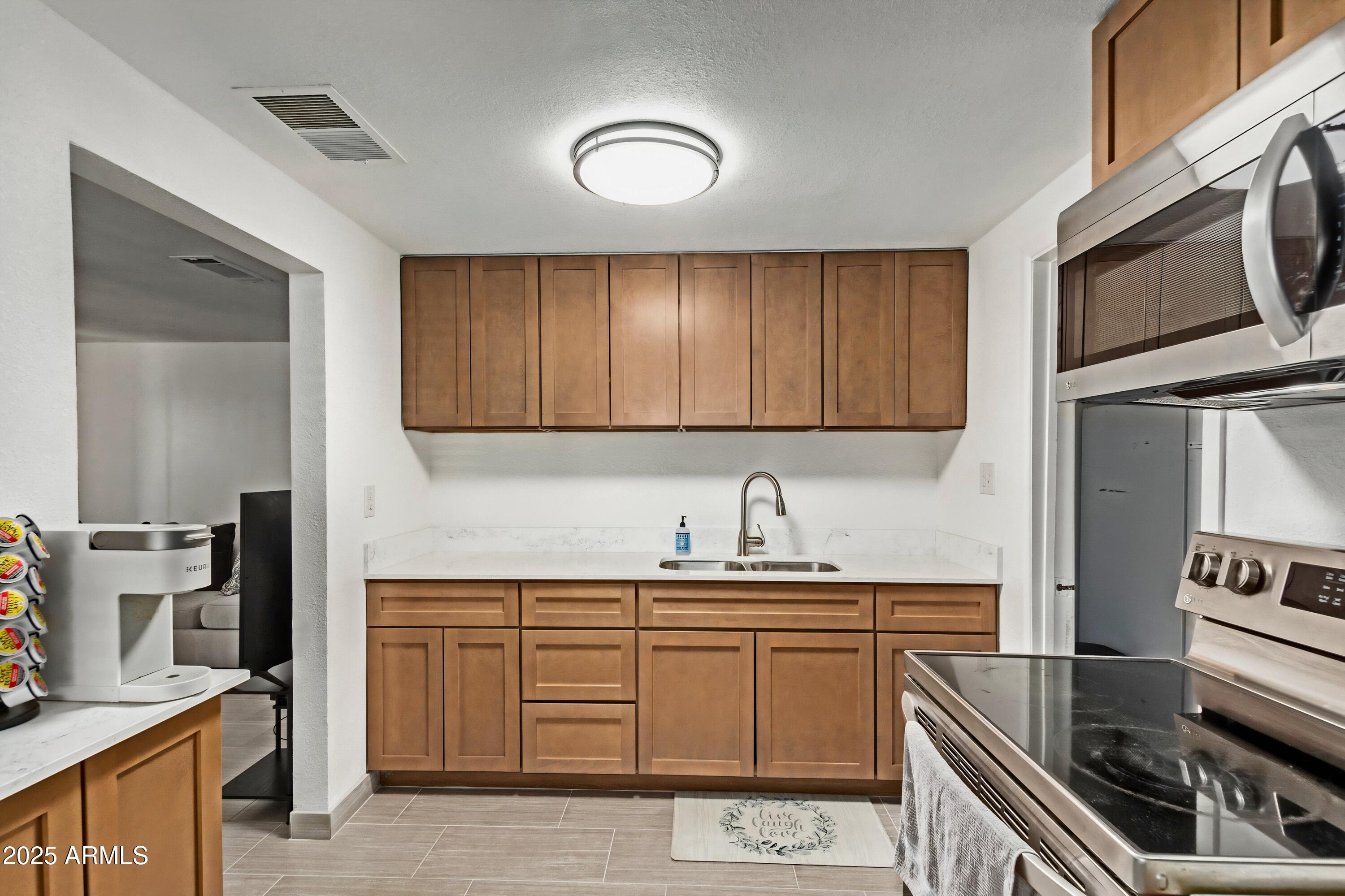 1221 East Alta Vista Road Phoenix, AZ 85042 - Photo 8 of 33 a kitchen with stainless steel appliances a stove sink and microwave
