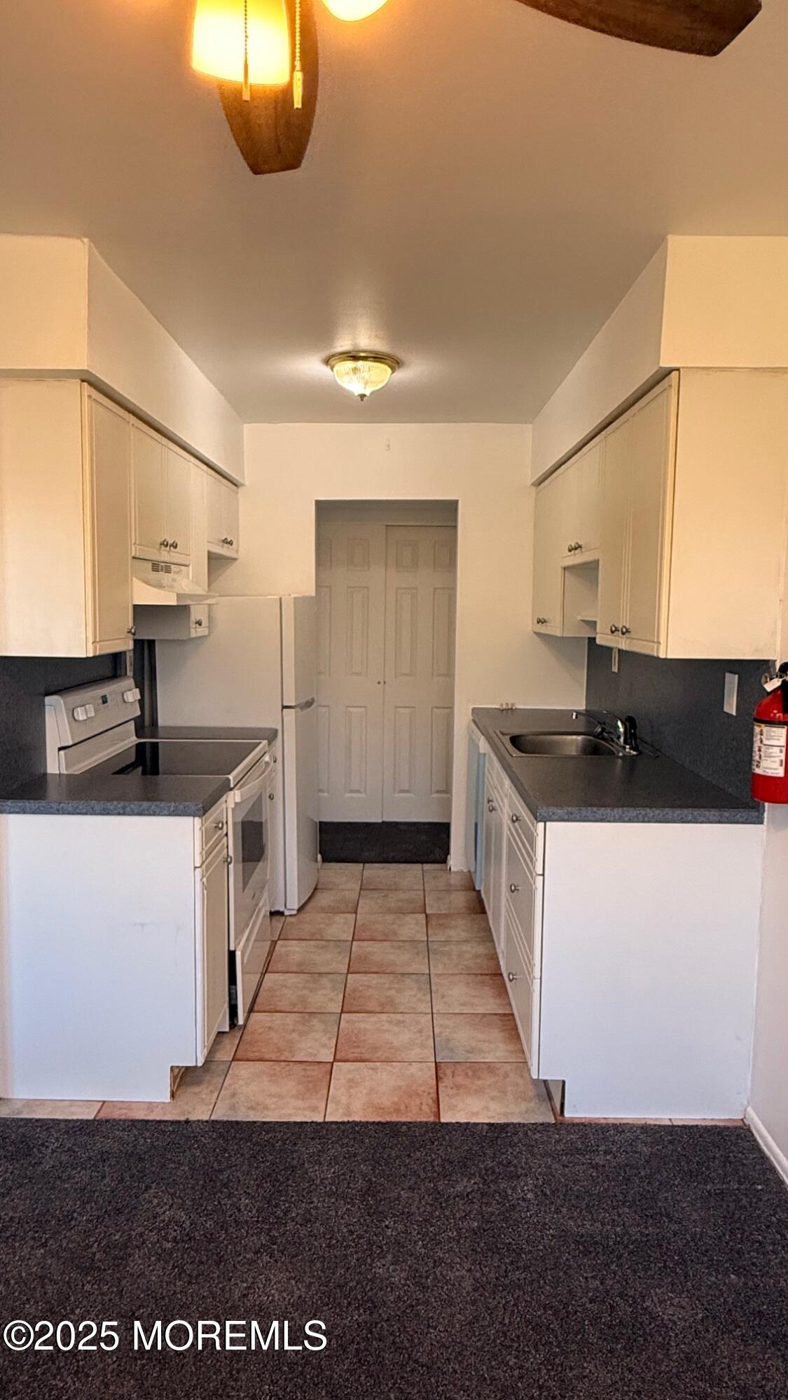 76 Manchester Court, Unit H Freehold, NJ 07728 - Photo 6 of 10 a kitchen with granite countertop a stove and a refrigerator
