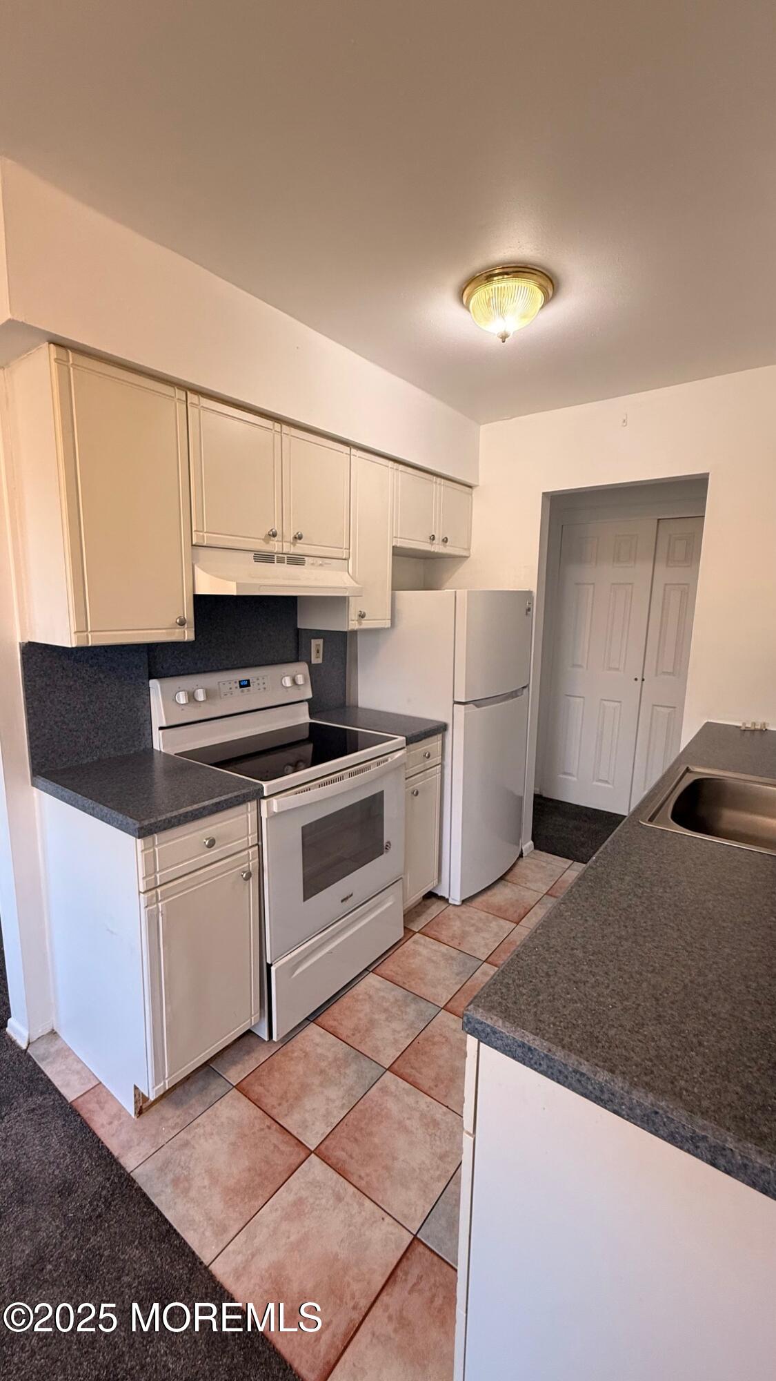 76 Manchester Court, Unit H Freehold, NJ 07728 - Photo 7 of 10 a kitchen with a refrigerator sink and cabinets