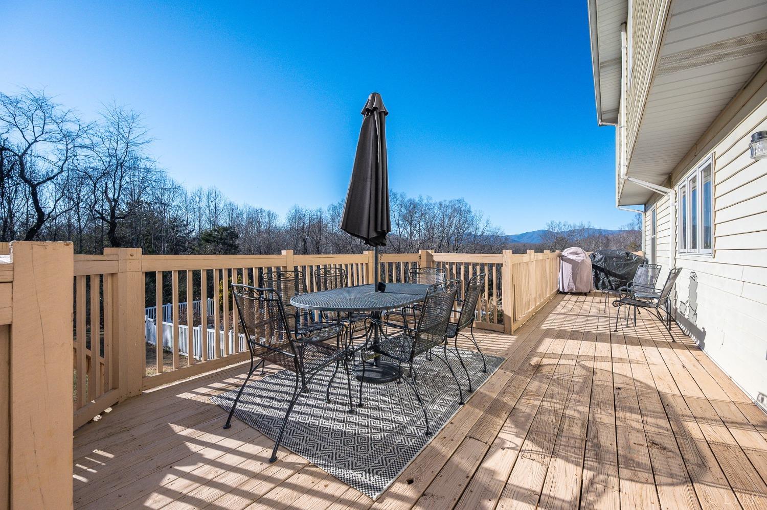 3520 Roaring Run Road Goode, VA 24556 - Photo 53 of 68 a view of a roof deck with table and chairs a barbeque with wooden floor and fence