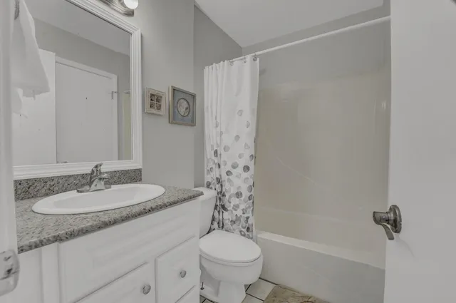 a bathroom with a granite countertop sink a toilet a mirror a shower and a bathtub
