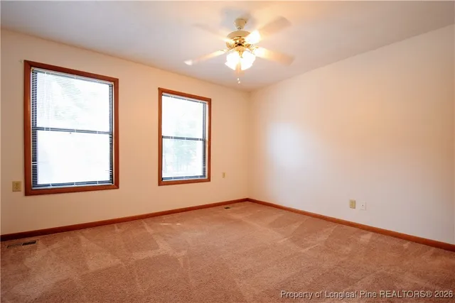 an empty room with windows and chandelier fan