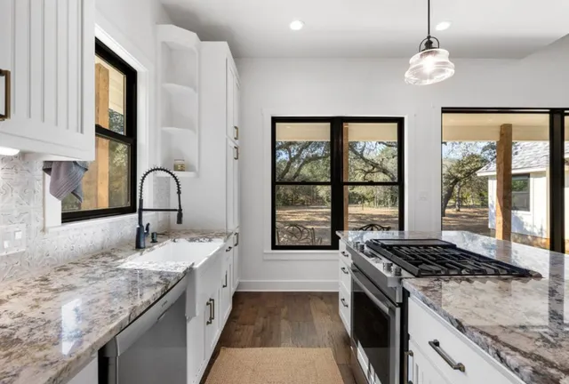 a kitchen with granite countertop a sink stove and cabinets