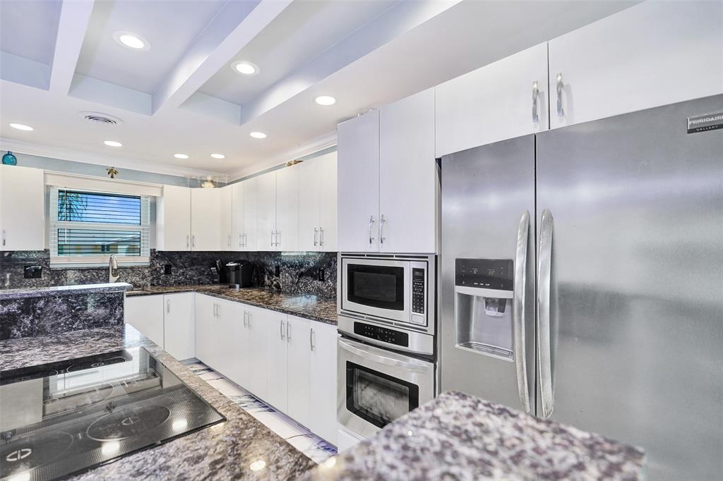 2330 Northeast 36th Street, Unit 9 Lighthouse Point, FL 33064 - Photo 14 of 48 a kitchen with stainless steel appliances kitchen island granite countertop a refrigerator and a sink