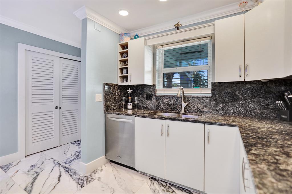 2330 Northeast 36th Street, Unit 9 Lighthouse Point, FL 33064 - Photo 15 of 48 a kitchen with granite countertop white cabinets and sink