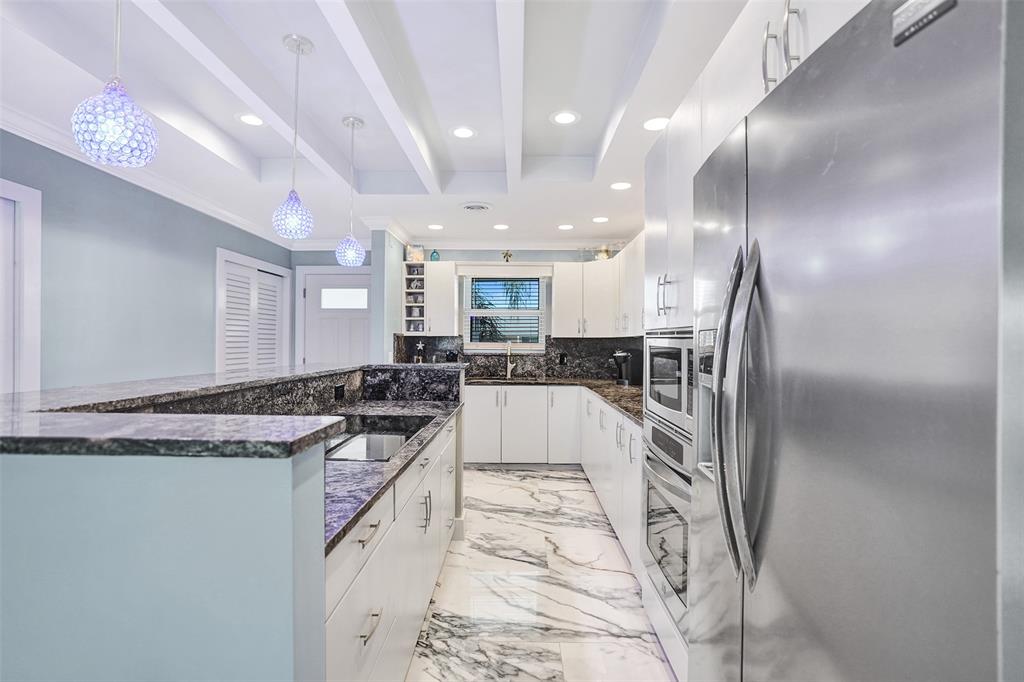 2330 Northeast 36th Street, Unit 9 Lighthouse Point, FL 33064 - Photo 17 of 48 a large white kitchen with kitchen island a large counter top space a sink and stainless steel appliances