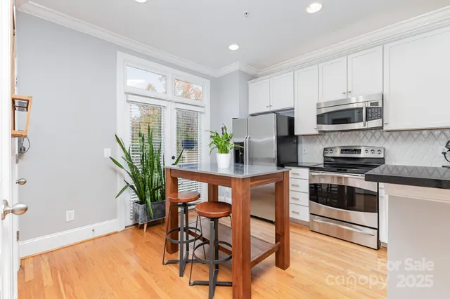 a kitchen with stainless steel appliances a dining table chairs stove and white cabinets