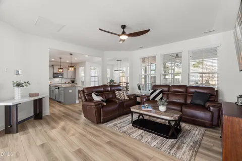 a living room with furniture kitchen view and a wooden floor