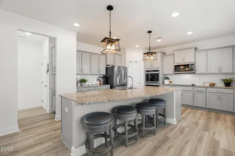 a kitchen with kitchen island granite countertop wooden floors and white cabinets