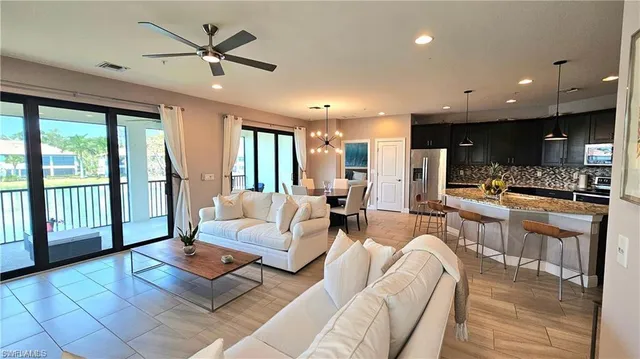 a living room with furniture kitchen view and a large window