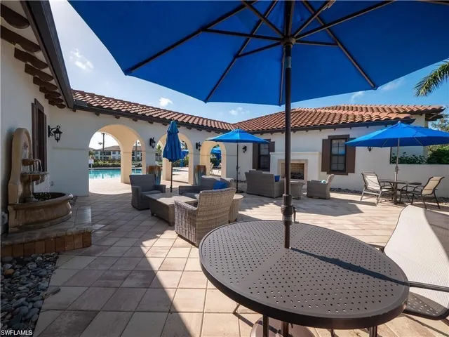 a view of a patio with table and chairs under an umbrella with potted plants
