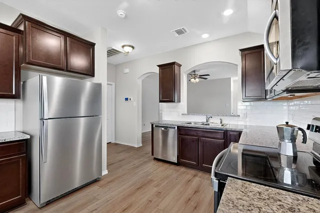 a kitchen with stainless steel appliances granite countertop a refrigerator a stove a sink and dishwasher