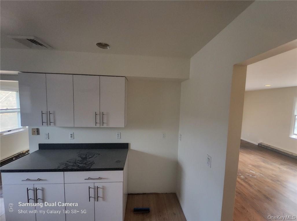 230 Prospect Road Monroe, NY 10950 - Photo 8 of 13 Kitchen with dark countertops, white cabinetry, and light wood-style floors