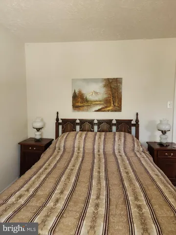 a bedroom with a bed and a lamp on dresser