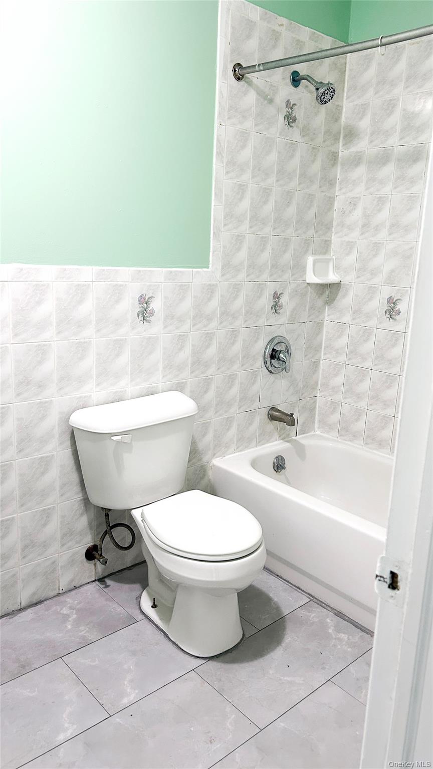 93-26 197th Street, Unit # 3 Queens, NY 11423 - Photo 12 of 14 Bathroom featuring shower combination, tile walls, and tile patterned floors