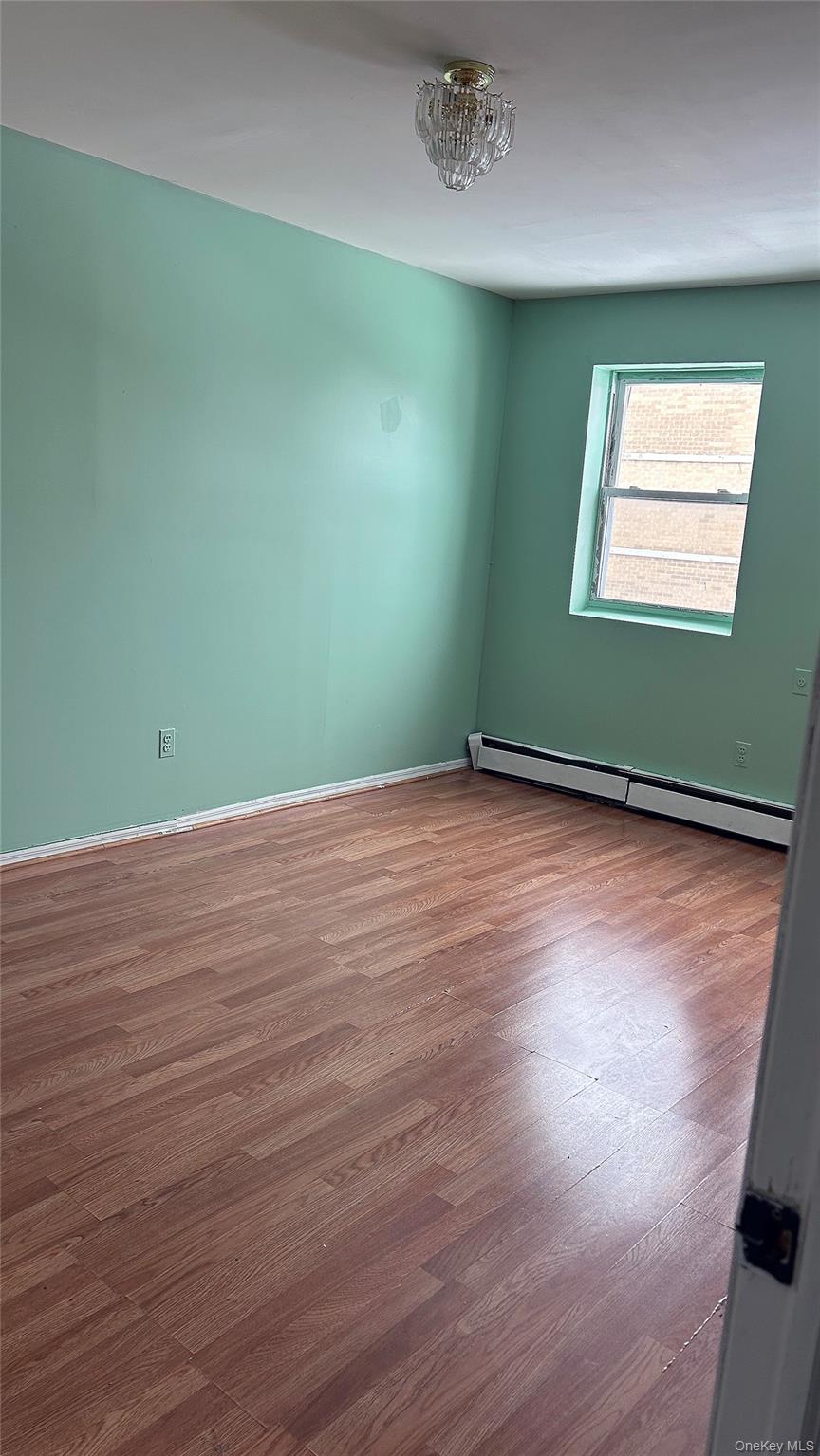 93-26 197th Street, Unit # 3 Queens, NY 11423 - Photo 4 of 14 Empty room featuring a baseboard heating unit and dark wood-style flooring