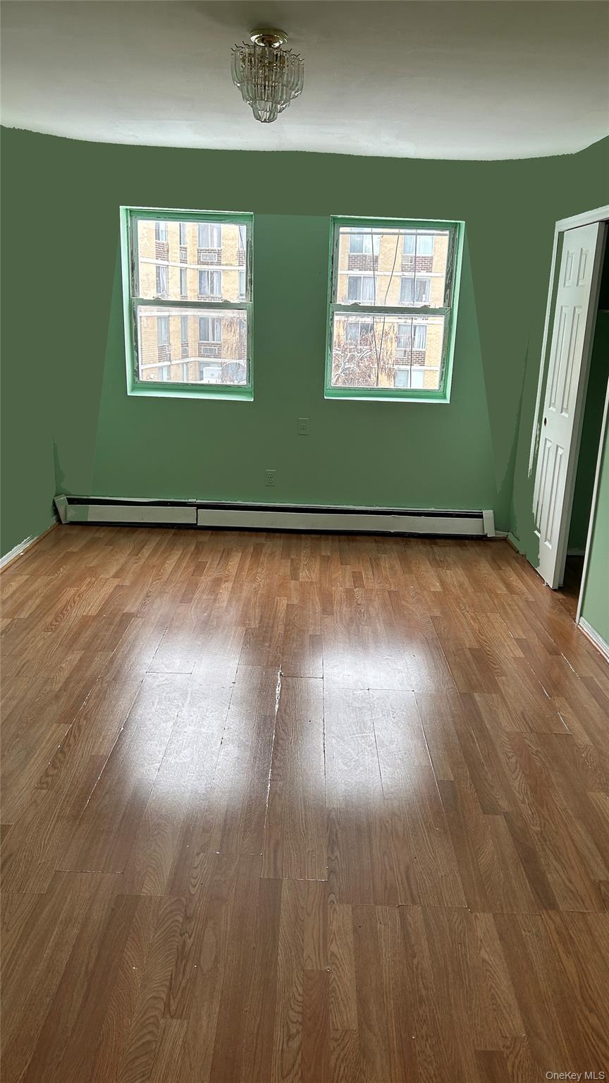 93-26 197th Street, Unit # 3 Queens, NY 11423 - Photo 6 of 14 Empty room with healthy amount of natural light, wood finished floors, and baseboard heating