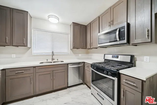 a kitchen with cabinets stainless steel appliances and sink