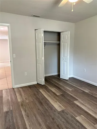 an empty room with wooden floor chandelier fan and windows