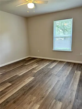 an empty room with wooden floor closet and windows