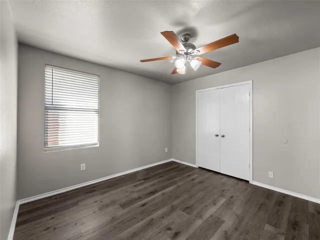 a view of an empty room with window and wooden floor