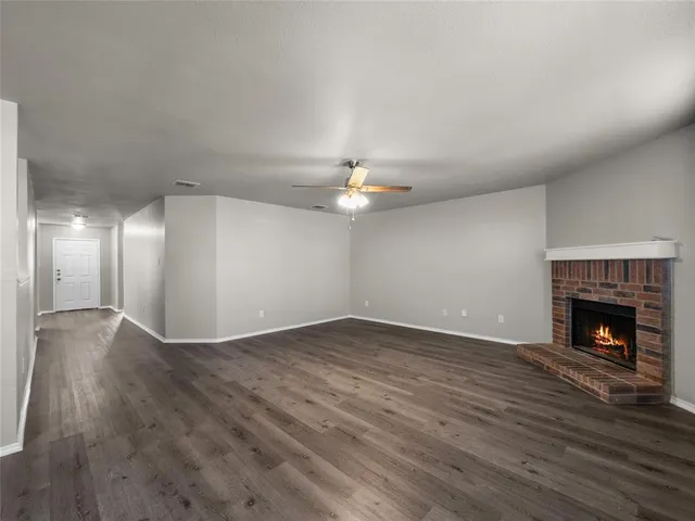a view of an empty room with wooden floor fireplace and a window