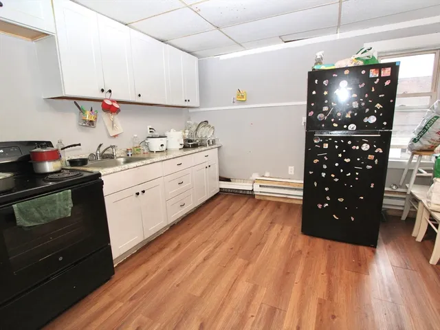 a kitchen with stainless steel appliances granite countertop a refrigerator a stove a microwave oven a sink and dishwasher with wooden floor