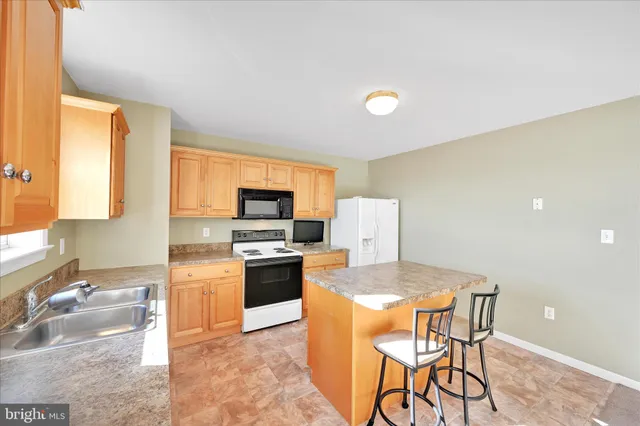 a kitchen with stainless steel appliances granite countertop a stove top oven a sink a dining table and chairs with wooden floor