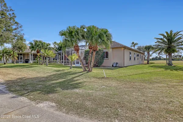 a view of a house with a yard and palm trees