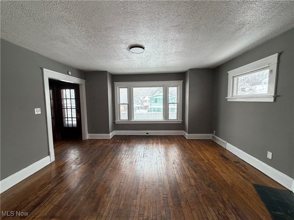 16309 Nela View Road Cleveland, OH 44112 - Photo 4 of 29 Spare room featuring dark wood finished floors, a textured ceiling, and plenty of natural light