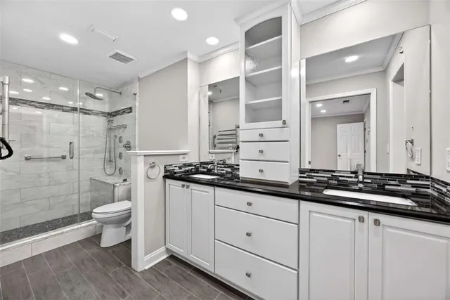 a bathroom with a double vanity sink toilet and shower