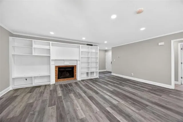 a view of an empty room with wooden floor fireplace and a window