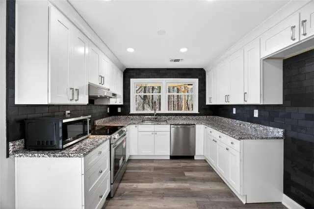 a kitchen with granite countertop sink stainless steel appliances and cabinets