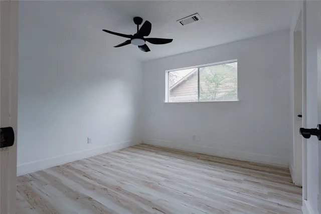 an empty room with wooden floor cabinet and windows