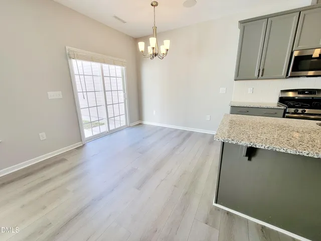 an empty room with wooden floor cabinet and windows