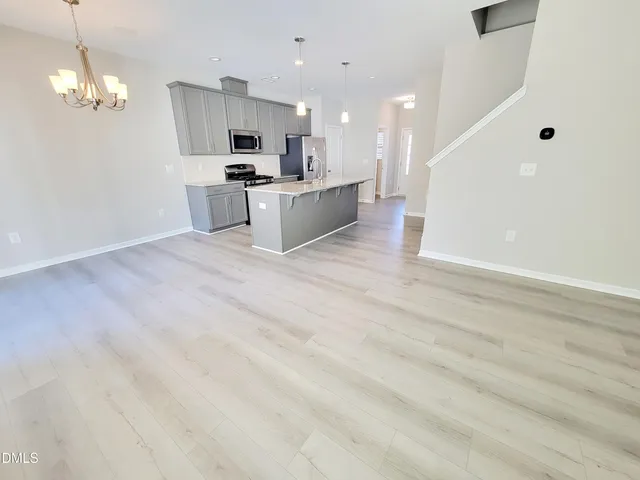 a view of kitchen with microwave a stove wooden floor and cabinets